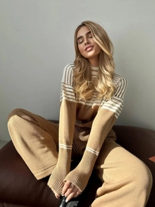 Détail d'un haut en tricot rayé kaki et d'un pantalon large porté par un mannequin