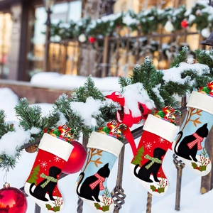 Détail de chaussettes de Noël pour animaux avec broderie chat et chien sur clôture enneigée