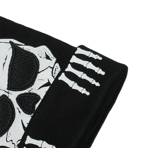 Close-up of winter knit beanie showing white skull and skeleton hand print on black fabric