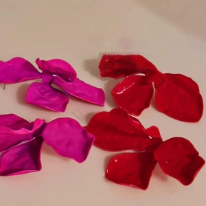 Macro view of large 3D flower petal earrings in matte rose pink and glossy red finishes