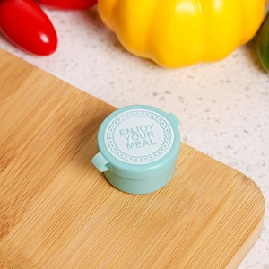 Close-up of mint green round mini sauce container with Enjoy Your Meal embossed on lid