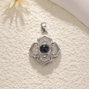 Detailed view of silver flower pendant featuring a dark gemstone and zircon embellishments