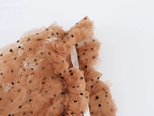 Dettaglio di elegante tulle marrone a pois neri con delicate texture a balze