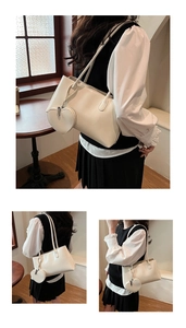 Detail of creamy white leather shoulder bag with a heart shaped charm pouch for women