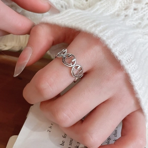 Detailed view of silver smiley face ring worn over a cozy white knit sweater