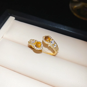 Detail view of a gold-plated snake-shaped open ring with tiger eye stones and zircons