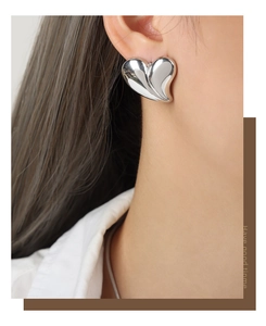 Gros plan sur des boucles d'oreilles cœur argentées avec texture plissée élégante
