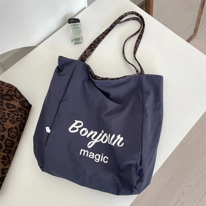 Detail of navy blue canvas tote bag with Bonjour magic print and leopard straps
