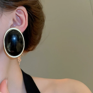 Gros plan sur des boucles d'oreilles rétro en résine noire avec cadre en métal doré