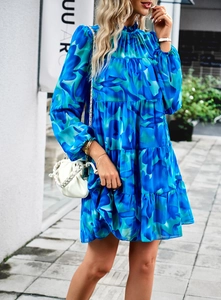 Détail d'une robe courte fleurie bleue et verte avec volants superposés et manches longues
