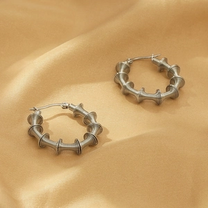 Detailed macro view of silver twisted spiral wire hoop earrings on gold silk background