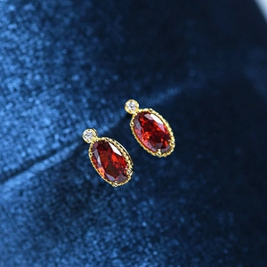 Macro shot of French vintage gold stud earrings with oval red gems on blue velvet