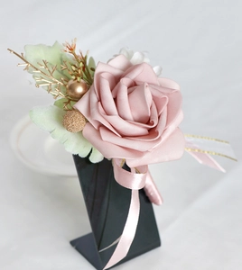 Detailed view of dusty pink PE rose boutonniere with gold accents on a black stand