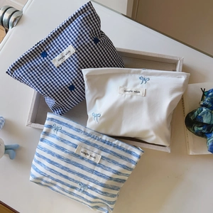 Close-up of blue striped and plaid makeup bags with bow embroidery and zip closure
