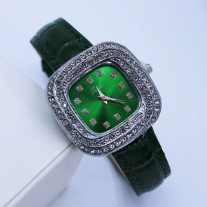 Vue macro d'une montre carrée en argent avec cadran vert et strass brillants