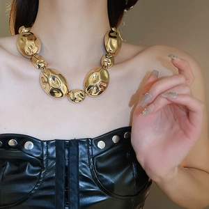 Close-up of golden chunky pebble necklace with irregular hammered texture on model