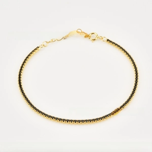 Detail of gold tennis bracelet with round black zircon stones and lobster clasp