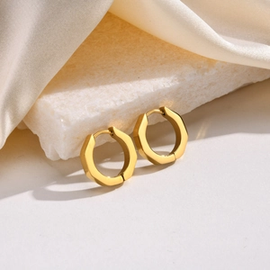 Minimalist gold titanium steel octagonal hoop earrings on a marble stone background