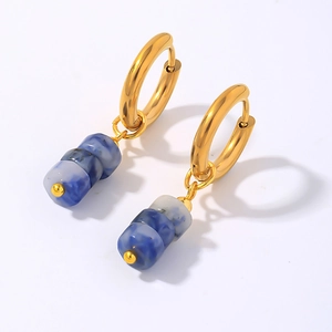 Détail de boucles d'oreilles dorées avec pendentifs cylindres en résine marbrée bleue