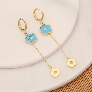 Detail of long tassel earrings with blue marble flowers and gold chain on ceramic plate