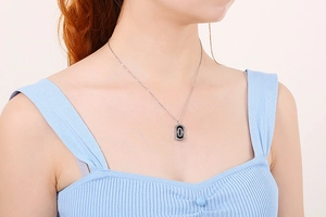 Detail of model wearing a silver paperclip necklace with double oval black and silver pendant