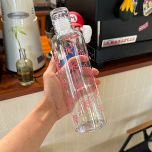 Close-up of clear heat-resistant plastic bottle with pink bow pattern held in hand