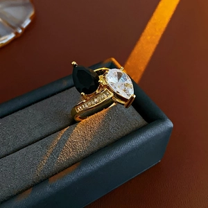 Détail d'une bague dorée ornée de pierres noires et transparentes en forme de poire