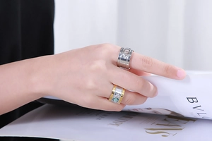 Detail of wide stainless steel rings with champagne and green crystals on hand