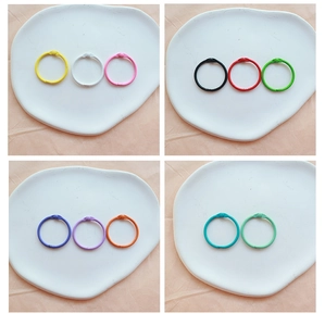 Colorful metal loose-leaf binder rings displayed in a ceramic plate with various vibrant colors