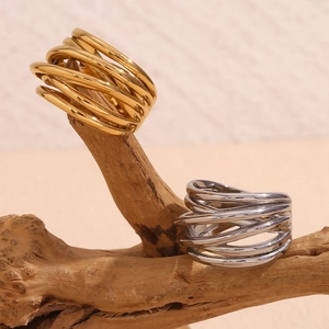 Macro detail of twisted woven rings in gold and silver finish on a natural wooden branch