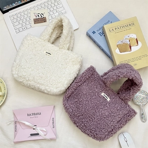 Detailed view of plush lamb wool handbags in cream and purple with brand woven labels
