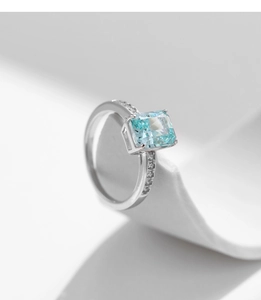 Macro detail of silver ring featuring light blue square cut stone and micro side stones