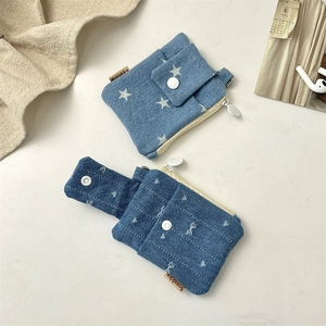 Detail of denim card holders with snap button and metal hook on a minimalist desk