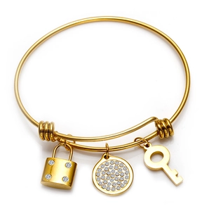 Detail of adjustable gold wire bracelet with crystal padlock, key, and round charm