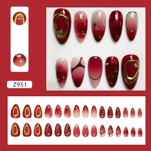 Deep red almond press-on nails with 3D gold foil borders and star nail art accents