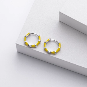 Detailed view of yellow enamel bamboo-style sterling silver hoop earrings on a stone base