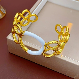 Close-up of golden circular link bangle with white enamel detail on jewelry box lid