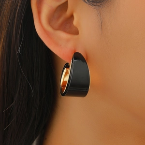 Macro view of C-shaped leopard earrings with black enamel and polished gold metal