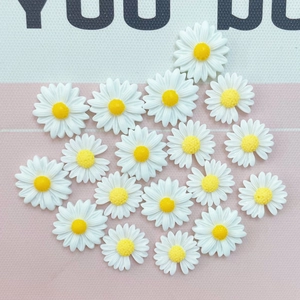 Detailed top view of white resin daisy flower charms for DIY crafts and hair accessories