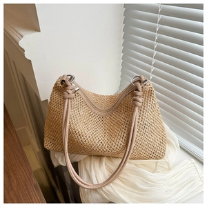 Detail of hand-woven straw tote with leather handle and decorative silver rings
