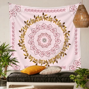 Pink bohemian tapestry with floral mandala pattern hanging above a cozy sofa bed setup