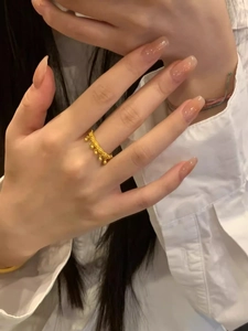 Detailed view of a gold tassel beaded ring worn on index finger with a minimalist design