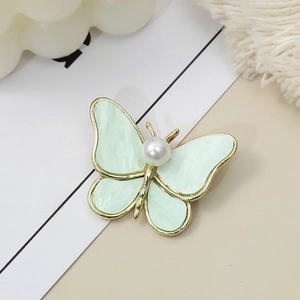 Elegant gold butterfly brooch with light green wings and a white pearl accent