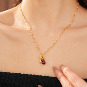 Detail of red agate gourd pendant on an 18k gold-plated necklace worn by a model