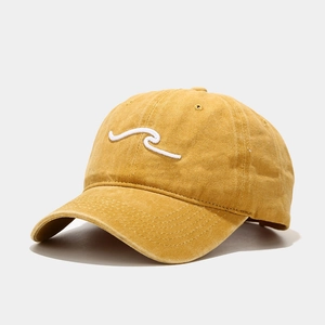 Détail d'une casquette en coton lavé jaune avec broderie vague blanche et coutures fines