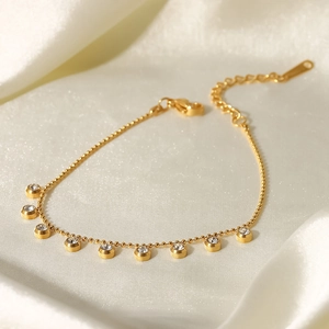 Detailed view of a gold-plated round bead anklet with sparkling zircon charms on silk
