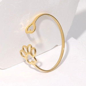 Dettaglio macro del bracciale in acciaio inossidabile dorato con zampa di gatto e cuore