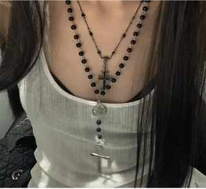 Close-up of layered black bead necklace with vintage cross and star pendant details