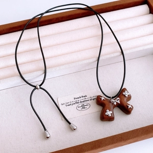 Detailed close-up of retro wooden bow pendant with silver star accents and adjustable cord