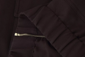 Macro shot of dark brown canvas fabric with metal zipper detail and ribbed elastic texture